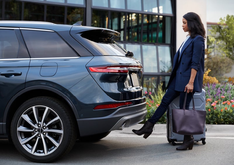A woman with luggage and a bag opens the available hands-free liftgate by kicking her foot under the bumper | Randy Marion Lincoln in Statesville NC