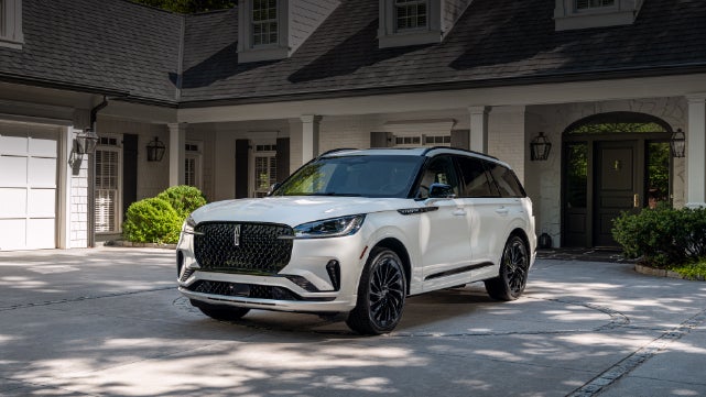 A white 2026 Lincoln Aviator® SUV is parked in the driveway of a luxury home. | Randy Marion Lincoln in Statesville NC
