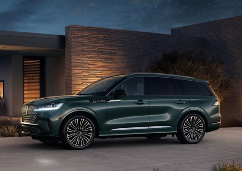 A green 2027 Lincoln Aviator® SUV is parked outside a contemporary home. | Randy Marion Lincoln in Statesville NC