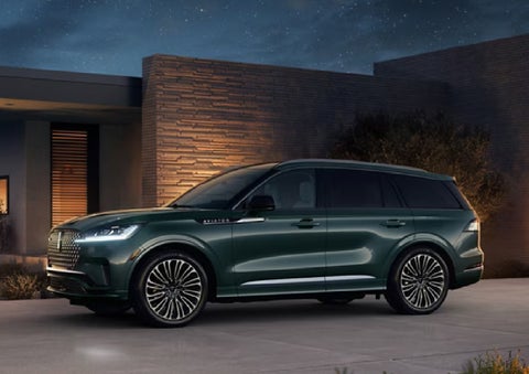 A green 2027 Lincoln Aviator® SUV is parked outside a contemporary home. | Randy Marion Lincoln in Statesville NC