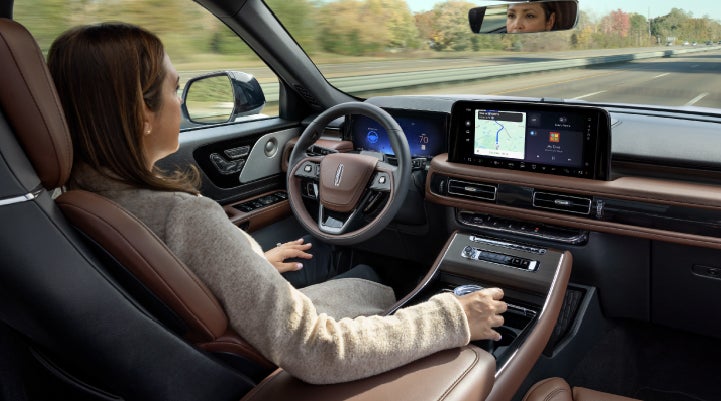 A 2027 Lincoln Aviator® SUV is being driven hands-free on a highway lined with trees. | Randy Marion Lincoln in Statesville NC