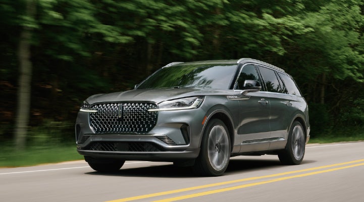 A 2027 Lincoln Aviator® SUV is being driven down a road lined with trees. | Randy Marion Lincoln in Statesville NC